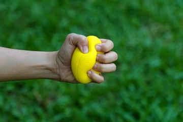 Hand holding stress ball and squeezing for relieve stress and strengthen the muscles of hand and wrist.