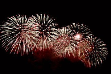 Flashes of red and white fireworks against black sky