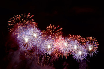 Flashes of red and purple fireworks against black sky