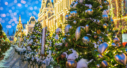 Stylish garland lights on christmas trees fir branches with christmas decorations at front of a building at european city street. Festive street decor in winter holidays