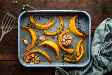 Baking tray with roasted pumpkin with garlic and herbs.