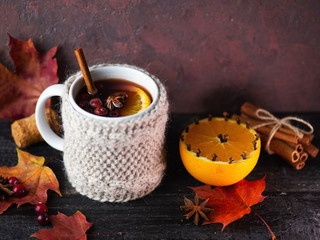Knitted mug of traditional winter and autumn drink mulled wine or sangria on the table with dry...