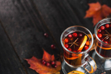 Hot alcoholic winter and autumn drink mulled wine or sangria on a dark table with orange, cinnamon, anise and cranberries copy space