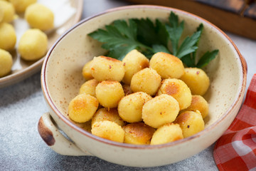 Naklejka na ściany i meble Beige bowl with italian pan fried potato gnocchi, close-up, selective focus