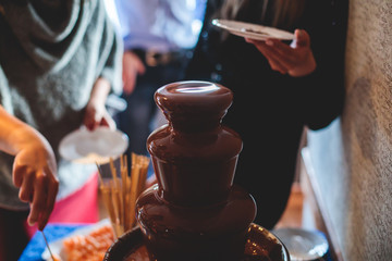 Vibrant Picture of Chocolate Fountain Fontain on a children kids birthday party with a kids playing around and dipping marshmallows and fruits into the fountain