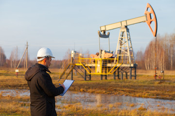 Engineer in a white helmet on an oil rig with a tablet. Oil production in Russia, Republic of...