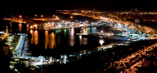 Fototapeta na wymiar Wonderful night panorama of the bay of Malaga with the port as the main motive lights of many colors make up the image and the beautiful reflection of the lights in the water