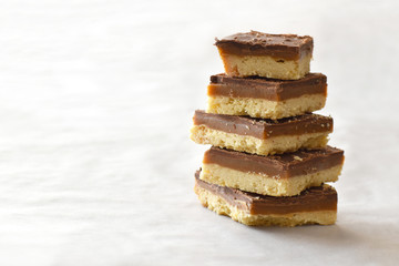 Millionaire's shortbread with chocolate and caramel on a parchment paper with copy space on the...
