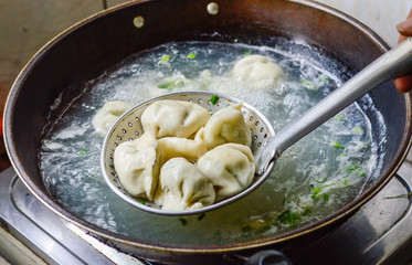 Cooking Chinese Dumplings in Boiled Water in a Wok.
