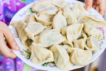 Two Hands Holding a Plate of Boiled Chinese Dumplings (Jiaozi)