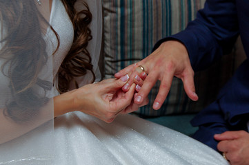 Obraz na płótnie Canvas Marriage hands with rings. The bride puts a ring on the finger of the groom during the wedding ceremony. The bride and groom exchange rings in wedding day. Photo closeup