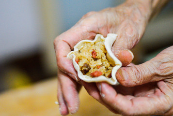 Hands Holding Chinese Shaomai Wrapper Filled with Sticky Rice & Pork. Shaomai is Traditional Chinese Food. Chinese Family Cooking Scene.
