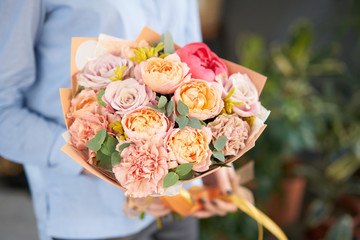 European floral shop. Beautiful bouquet of mixed flowers in womans hands. the work of the florist at a flower shop. Delivery fresh cut flower.