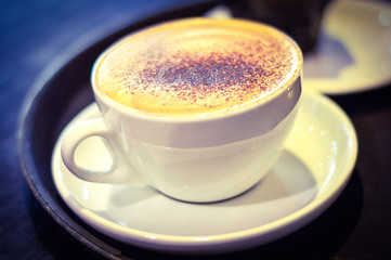 Closeup of a Cup of Cappuccino Placed on Table. Blur Background.