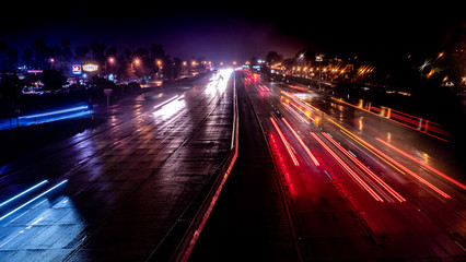 Light trails of cars driving at night on the freeway in rain