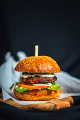 Freshly made forest burger with rucola, onions, grilled portobello and garlic souce on dark background