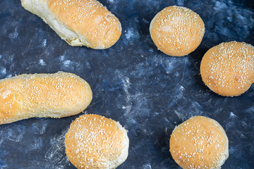 Buns cooked in the oven. Sprinkled with sesame seeds. Yeast dough. On a dark background. Copy space. Banner. 
