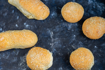 Buns cooked in the oven. Sprinkled with sesame seeds. Yeast dough. On a dark background. Copy space. Banner. 