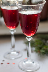 Red wine in transparent glasses. On a light background. Blurred background behind. Christmas tree branches. Copy space. 