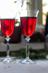 Red wine in transparent glasses. On a light background. Blurred background behind. Christmas tree branches. Copy space. 