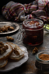 Jar of homemade plum jam marmalade with walnuts and french bread on the kitchen dark table. Healthy dessert snack recipes concept. 
