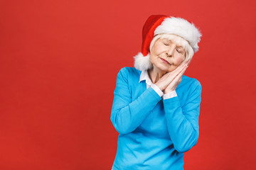 Senior aged grey-haired woman wearing Christmas Santa hat over isolated red background very happy and excited, having fun, smiling. Happy winner.