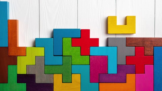 Top view on colorful wooden blocks folding on white wooden background, stop motion. The concept of logical thinking.