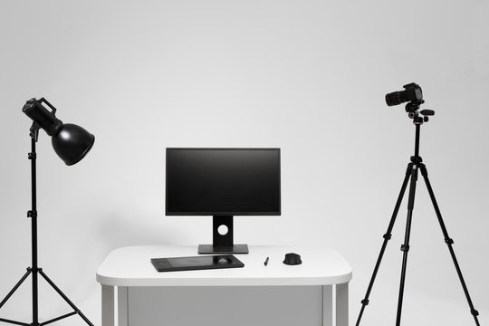 Photographer working place in photo studio with lighting equipment. Camera on the tripod. PC computer on desk. Designer working place.