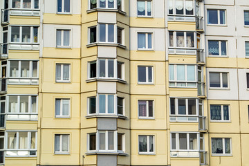Bottom view of a tall apartment building with various shades of beige walls.