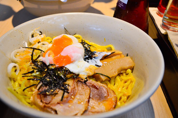 A bowl of Japanese tonkotsu ramen topped with seaweed, eggs and pork (tonkotsu)