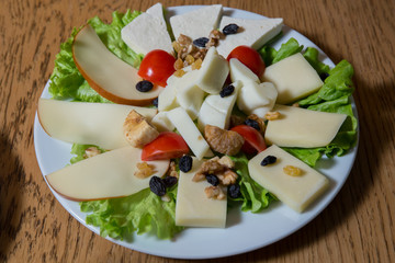 Top view . Cheese plate with different kinds of cheese with thyme walnuts and tomatoes . Cheese plates served with bruised on a wooden board.