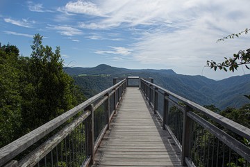 Breathtaking view of a wooden path over the beautiful tree covered mountains under the cloudy sky