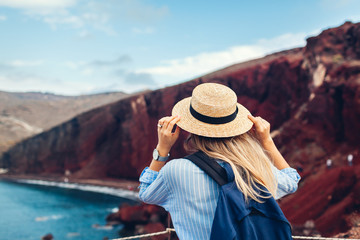 Tourist looking at Red beach landscape from view point in Akrotiri, Santorini island, Greece. Woman...