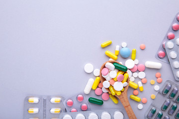 Colored pills and tablets in blister on a grey background, top view