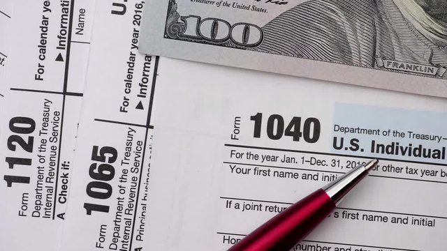 USA Tax Form 1040, 1120, 1065 and dollar bills, close up. Slow motion.