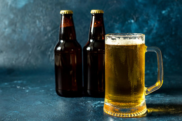 glass of cold beer and bottle on gray stone table