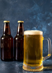 glass of cold beer and bottle on gray stone table