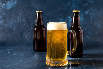 glass of cold beer and bottle on gray stone table
