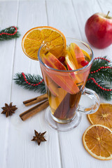 Christmas drink. Mulled wine with apples, orange, cranberries and spices on the white wooden...