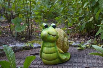Grüne Keramik Schnecke im Garten als Dekofigur.