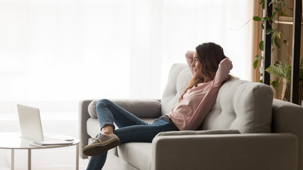 Happy woman relax on couch dreaming looking in window