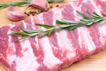 Raw fresh pork ribs with rosemary and spices on a wooden board. Fresh meat.