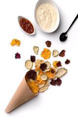 Crisp crunchy organic vegetable chips in paper cup. Oven-baked pumpkin, beetroot, squash, tomato, carrot chips snacks