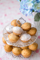dish glass bunk with cupcakes on the background of a bouquet of blurred