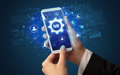 Female hand holding smartphone with IVR abbreviation, modern technology concept