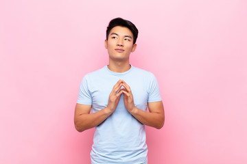 young chinese man scheming and conspiring, thinking devious tricks and cheats, cunning and...