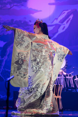 Traditional Japanese performance. Actress in white traditional kimono with long sleeves dancing, back view.