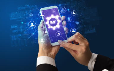 Female hand holding smartphone with IMF abbreviation, modern technology concept