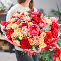 Red tones Beautiful bouquet of mixed flowers in womans hands. the work of the florist at a flower shop. Handsome fresh bouquet. Flowers delivery