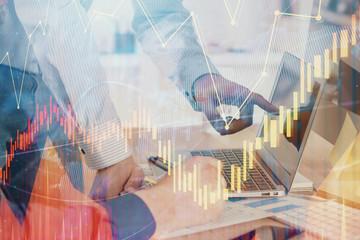 Double exposure of chart with businessman typing on computer in office on background. Concept of...